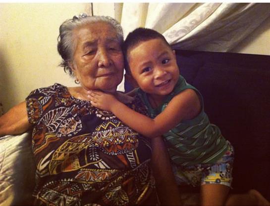 A joyful grandson embraces his grandmother at home, showcasing their close bond and love.