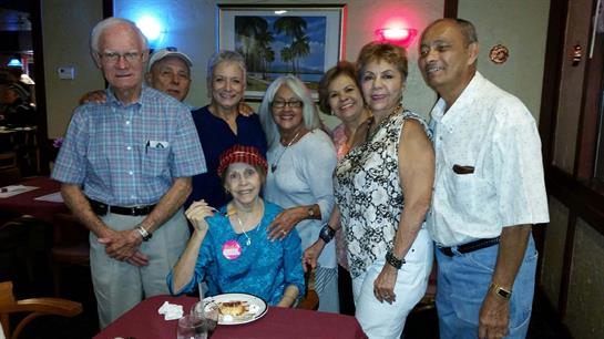 Friends and family gather around a table at a restaurant, smiling and enjoying their time together.