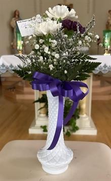 A vase with flowers and a purple ribbon