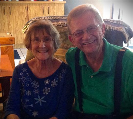 Happy older couple poses for a photo in a warm and inviting living room during a friendly visit.