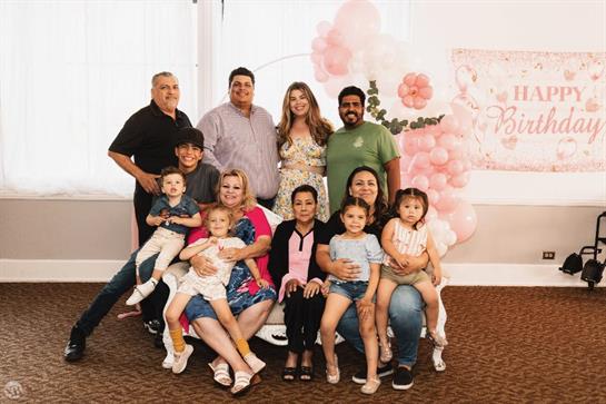 A large family comes together for a celebration, posing with smiles in a decorated venue.