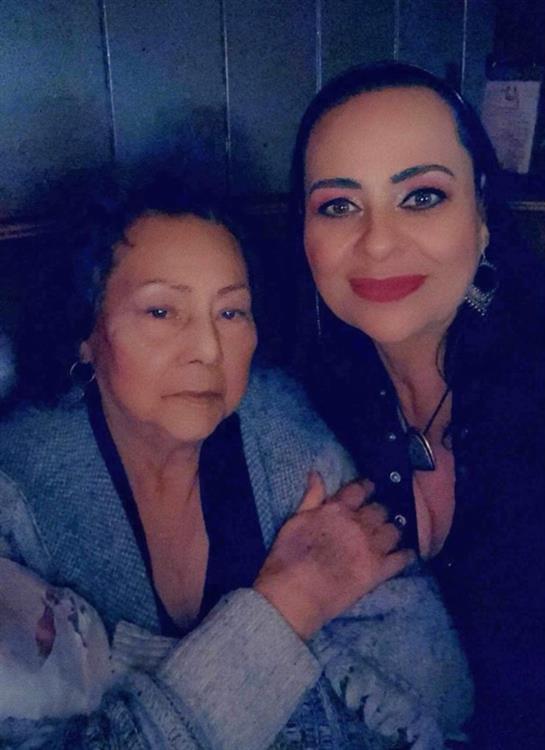 Two women embrace each other warmly during a family gathering in a cozy indoor setting.