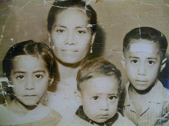 A mother poses with her three children, conveying warmth and connection in an old family portrait.