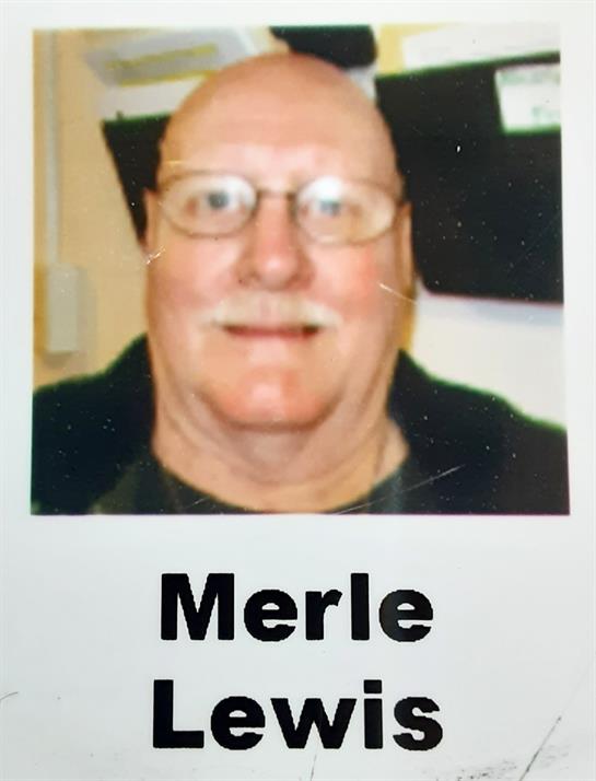 Smiling older man in glasses and a black jacket exudes warmth indoors.