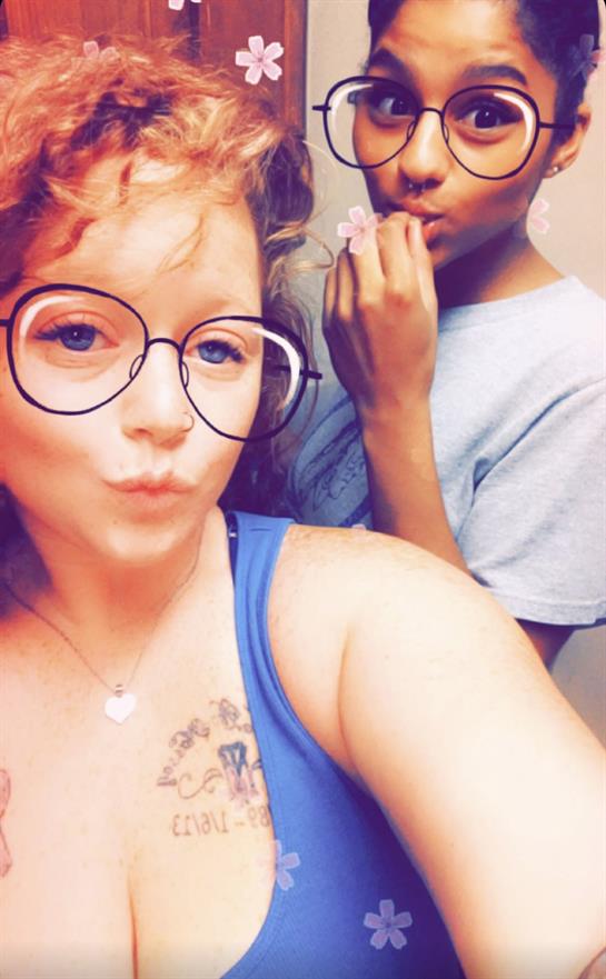 Two young adults enjoy each other's company, posing playfully in a casual indoor environment.