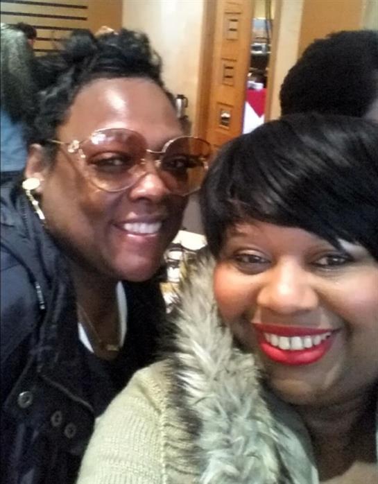 Two friends smile brightly while enjoying each other’s company in a relaxed cafe atmosphere.