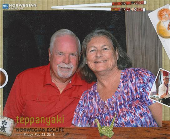 Smiling couple poses for a picture while dining at a teppanyaki restaurant on a cruise.
