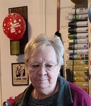 A woman in a room with balloons and a wall of wrapping paper