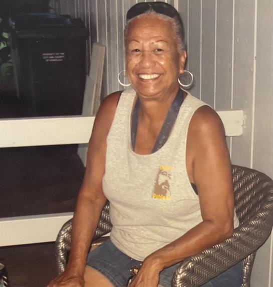 A joyful elderly woman with gray hair beams with happiness while seated at a gathering.