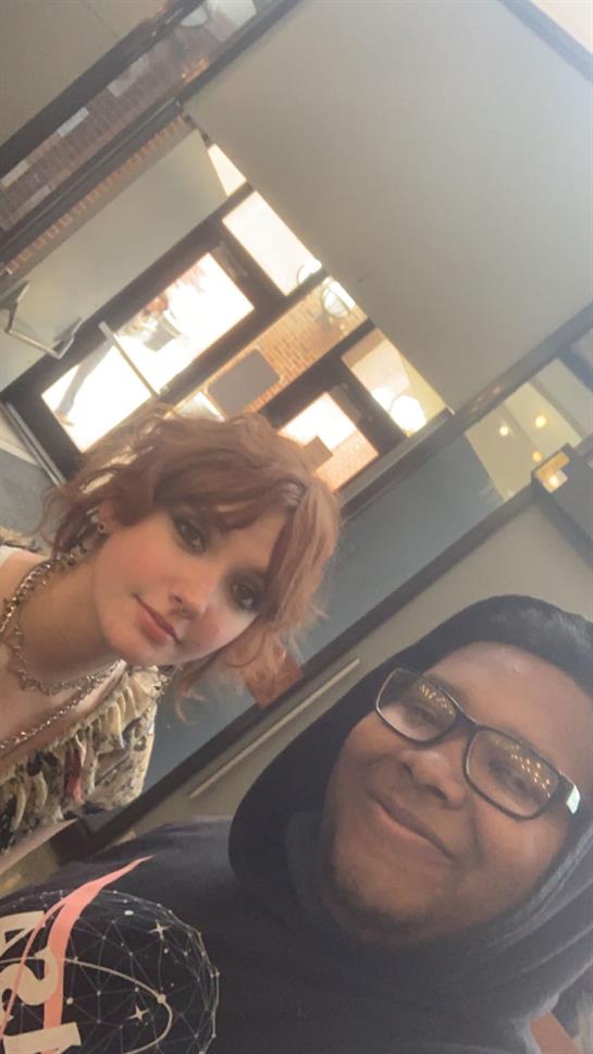 Women are smiling together in a cafe with bright natural light and modern decor.