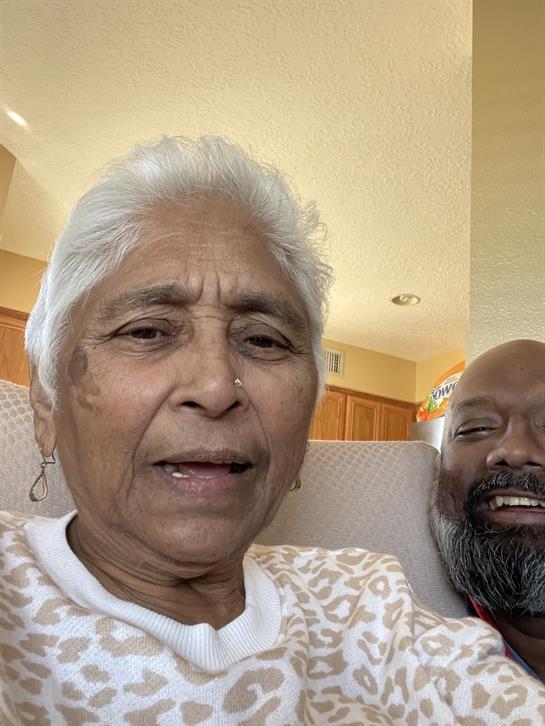 An elderly man and woman share a joyful moment together while sitting comfortably at home.