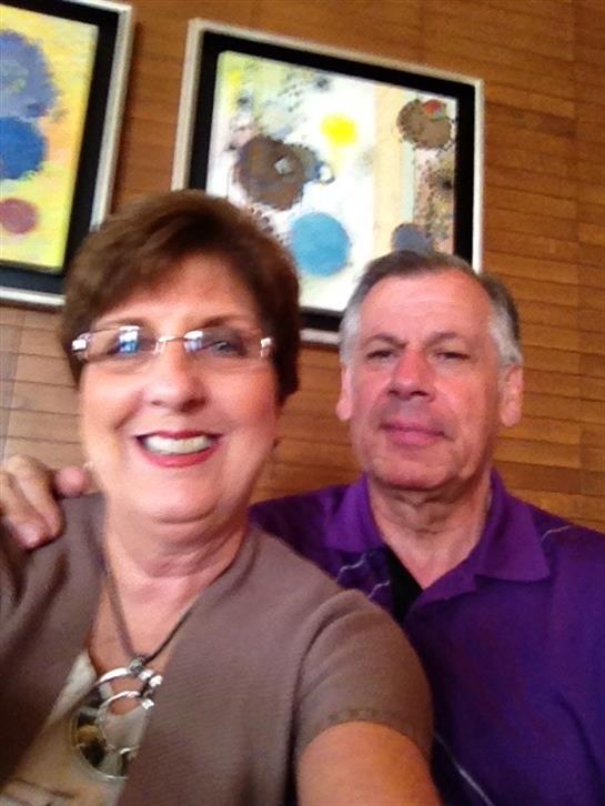 A couple smiles together in a warm restaurant, with colorful artwork decorating the walls.