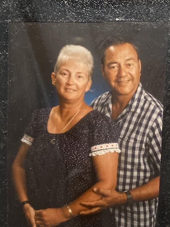 An older couple stands side by side, smiling warmly in a friendly atmosphere.