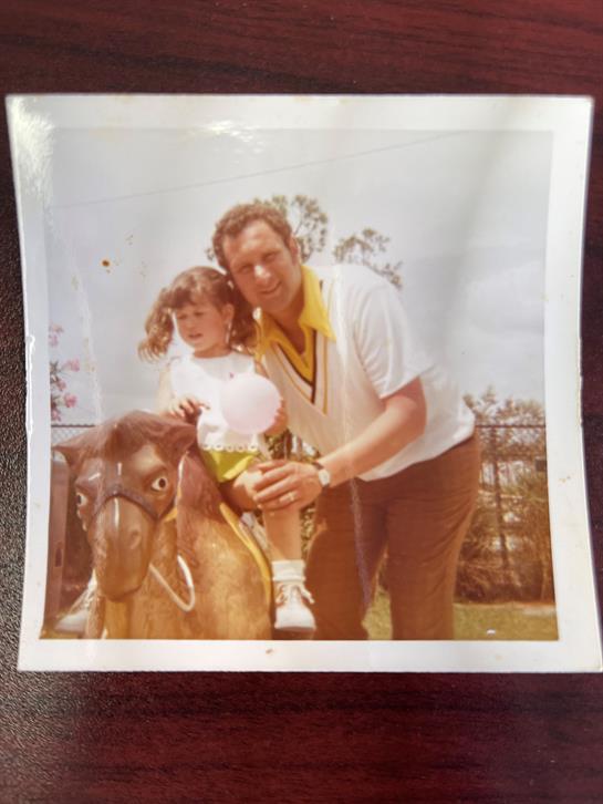 A joyful moment captured with a girl riding a pony alongside a smiling man outdoors in sunshine.