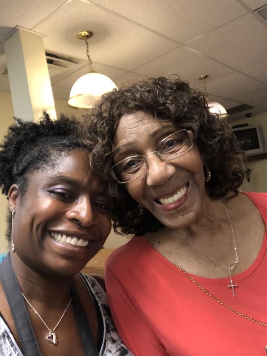 Two women share a joyful moment in a diner, enjoying each other's company and laughter.