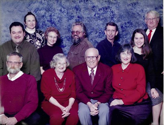 Relatives pose together in a studio, showcasing smiles and diverse outfits in a warm reunion.