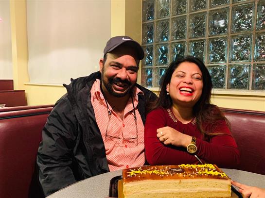 A man and woman sitting at a table with a cake