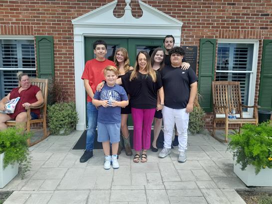 A joyful family poses together in front of a brick house, celebrating a special occasion.