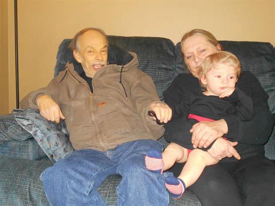 A man and woman sitting on a couch with a baby