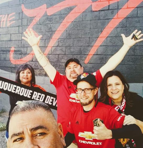 Group of enthusiastic fans showcase their support for Albuquerque Red Devils in vibrant location.