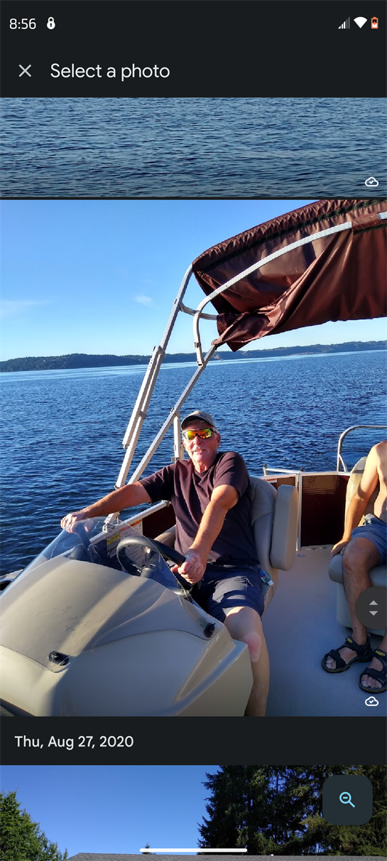 A man is happily driving a boat on an expansive body of water, with a friend beside him.