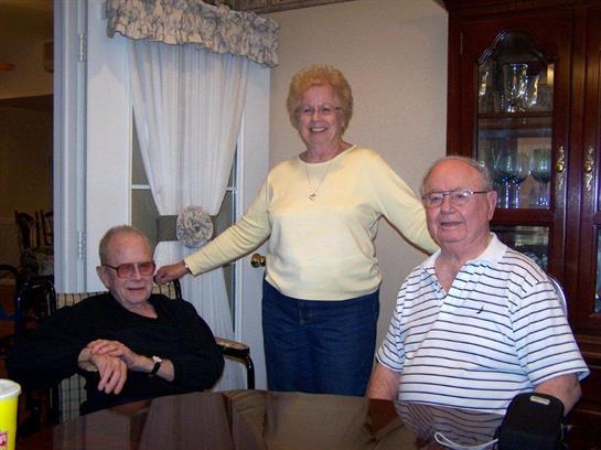 Three friends laugh and chat around a dining table on a cozy afternoon.