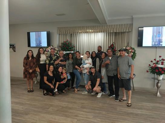Group of smiling individuals poses together in a warmly decorated hall, celebrating a joyful event.