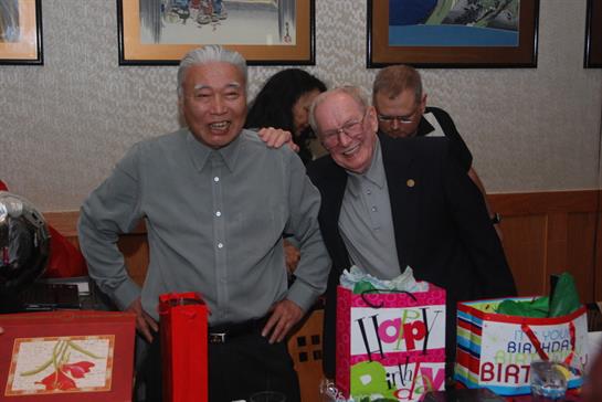 Friends enjoy a festive birthday gathering, surrounded by colorful gift bags and cheerful smiles.