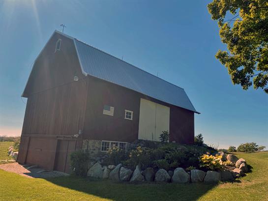 A barn with a large yard and a tree