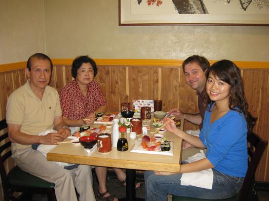 Four people are seated at a table, enjoying sushi together in a cozy restaurant atmosphere.