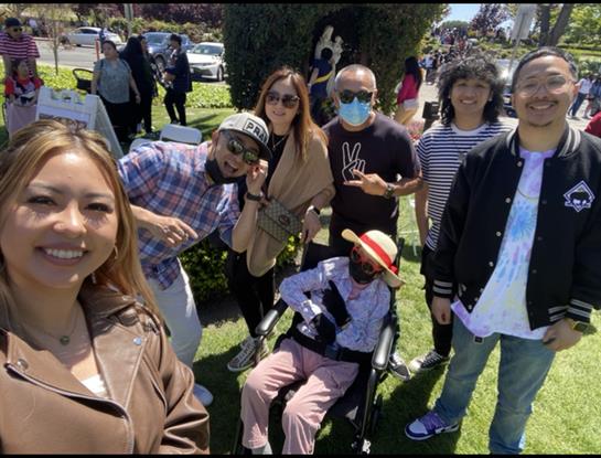 Friends happily gathered outdoors, posing for a cheerful photo in the sun.