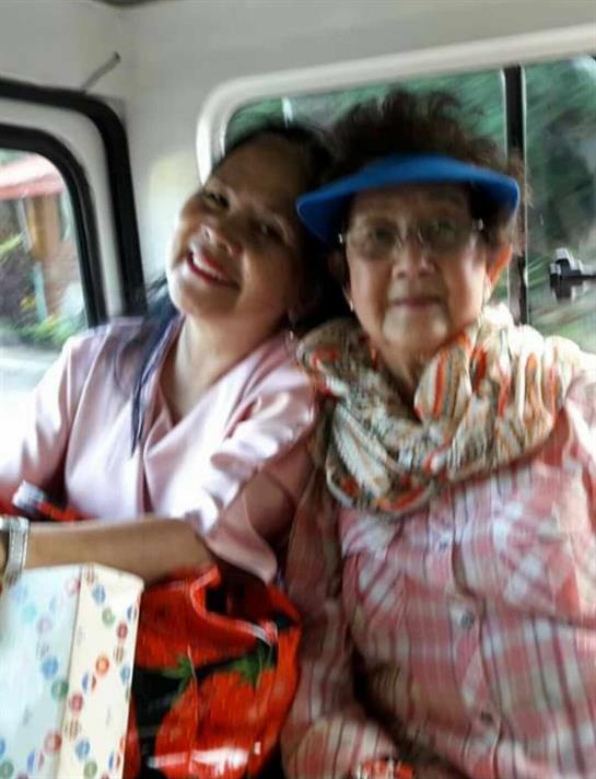Two women, one younger and one older, share laughter and companionship in a vehicle.