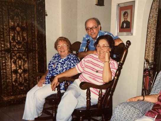 Three adults relax in rocking chairs, sharing stories and laughter in a warm home environment.