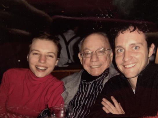 Three friends share laughter and warmth at a restaurant table during a lively evening outing.