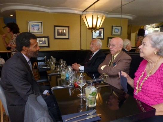 Group of four people converse over drinks in a cozy restaurant during the afternoon.