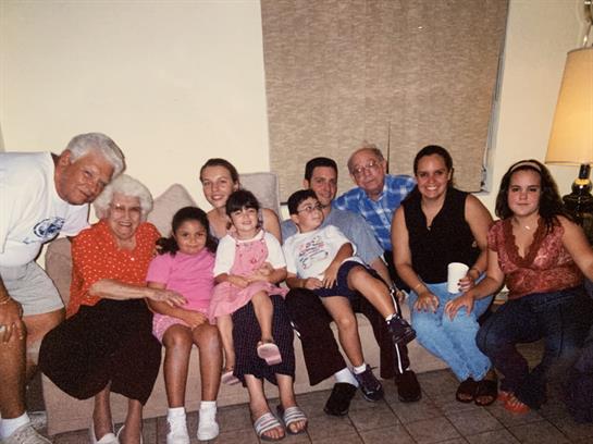Children, adults, and elderly members relax together, sharing smiles during a family reunion.