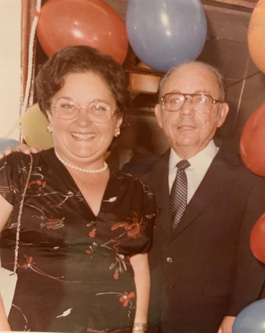 A joyful couple poses together at a party, celebrating among vibrant balloons and lively decor.