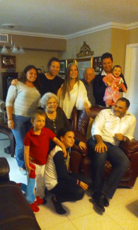 A warm family gathering takes place in a cozy living room with multiple generations present.