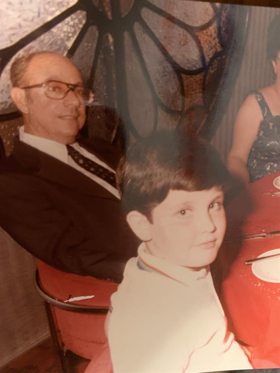 An elderly man in formal wear enjoys a meal with a young boy, radiating warmth and joy.