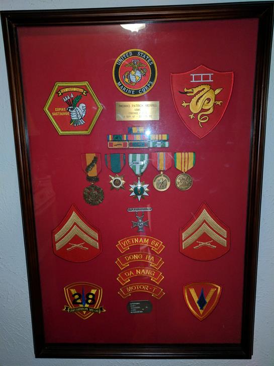 Military awards and insignia are arranged in a shadow box honoring a veteran's service.