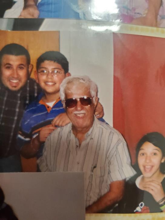 A group of family members, including children and an elderly man, share smiles during a celebration.