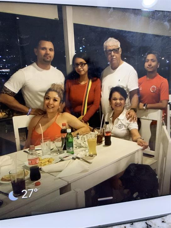 Six friends gather at a table, enjoying drinks, laughter, and a city view.