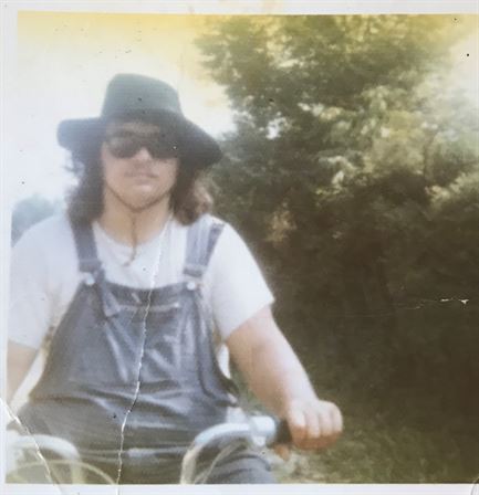 A man wearing sunglasses and a hat on a bicycle