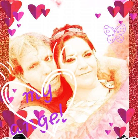 A happy couple embraces while surrounded by heart-themed decorations, smiling brightly together.