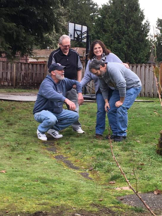 Friends gather in a backyard, laughing and playing together during a crisp fall day.