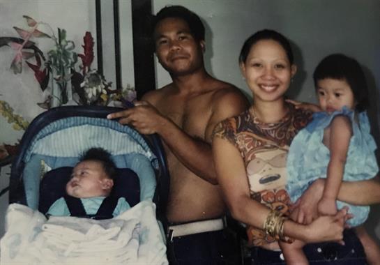 A family gathers joyfully in their living room, embracing their newborn and children fondly.