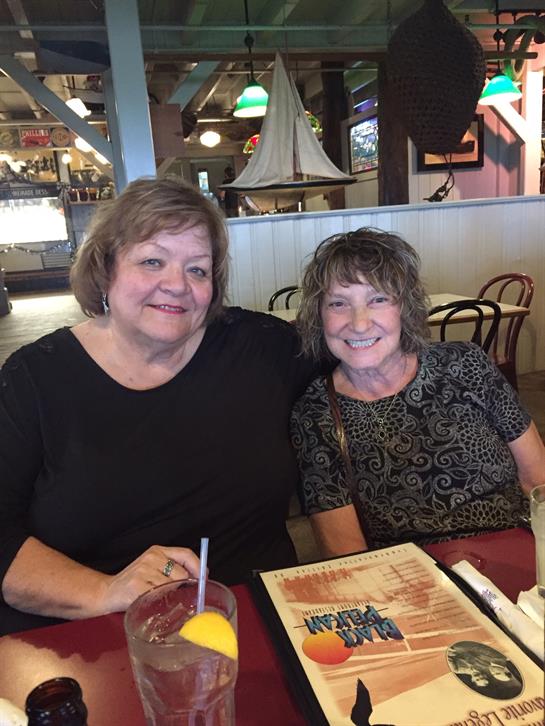 Two friends share a joyful moment while dining together at a lively restaurant.