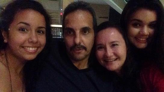 Three friends gather close, smiling and sharing a joyful moment during a relaxed night out.