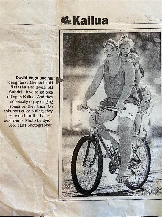 A man bikes through Kailua with his two daughters, enjoying a fun family outing on a bright day.