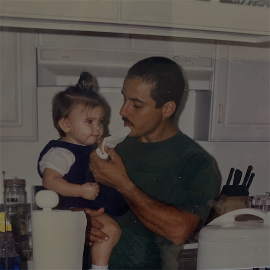 A father lovingly feeds his baby daughter in their cozy kitchen at home.